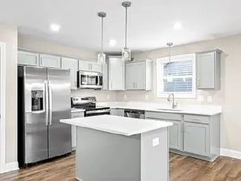 a kitchen with stainless steel appliances granite countertop a sink a stove a refrigerator cabinets and a kitchen island