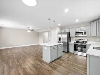 a kitchen with stainless steel appliances granite countertop a stove top oven a sink dishwasher and a refrigerator with wooden floor