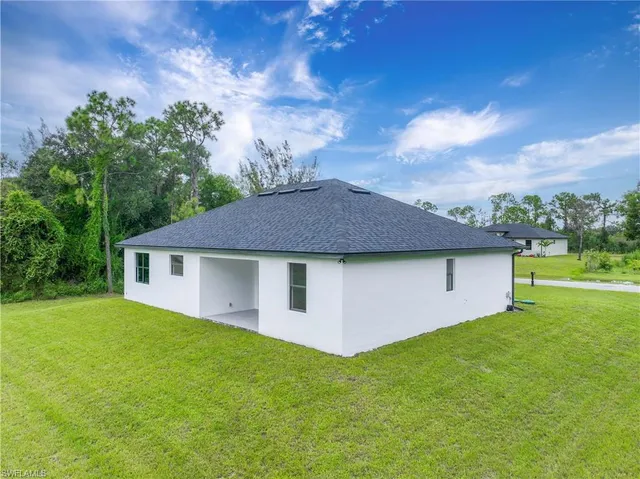 a backyard of a house with plants and large trees