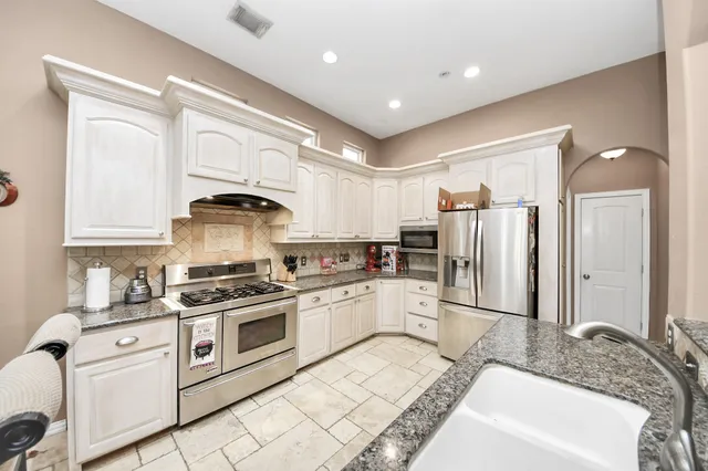 a kitchen with white cabinets and appliances