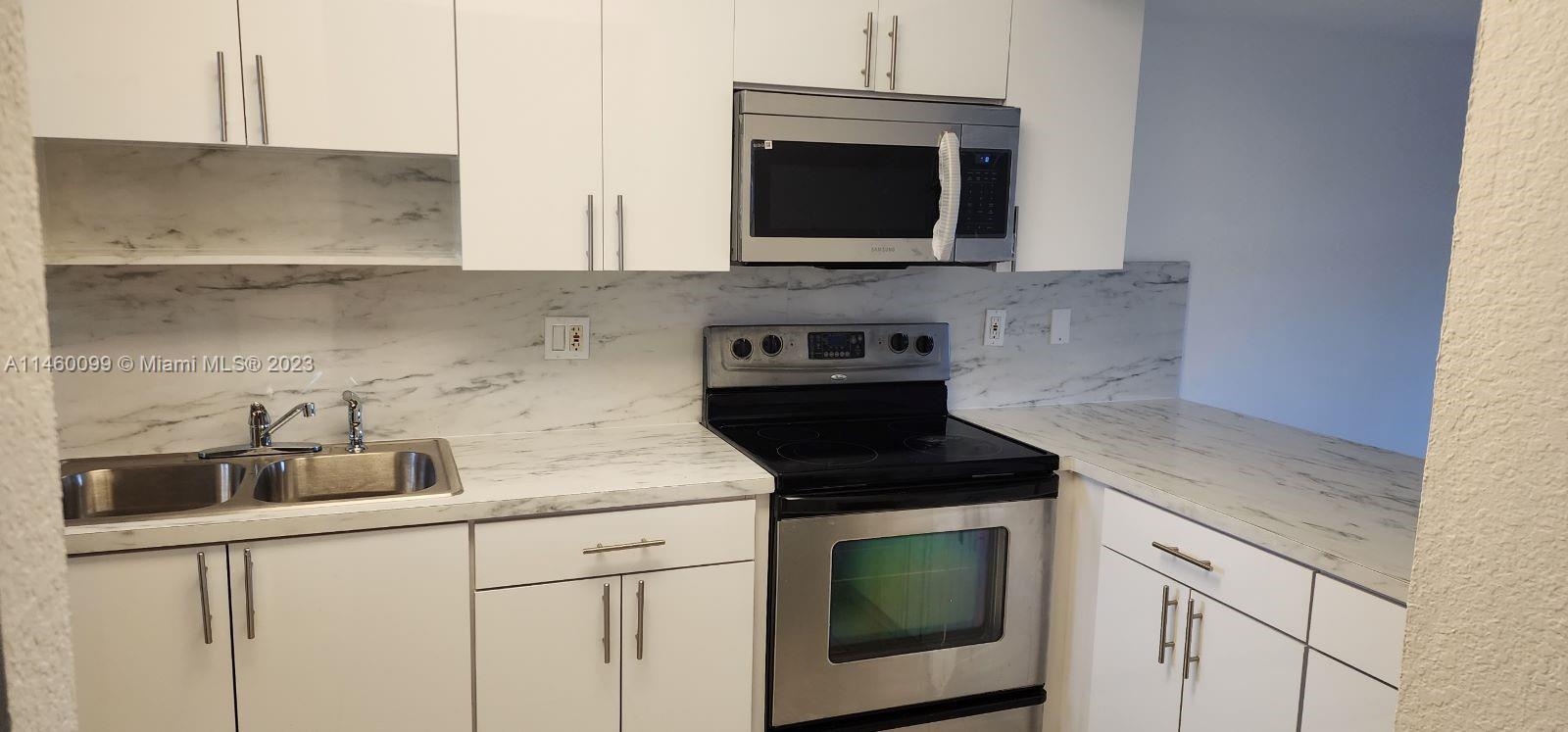 501 West 68th Street, Unit 4 Hialeah, FL 33014 - Photo 5 of 20 a kitchen with stainless steel appliances granite countertop a sink a stove a microwave and cabinets