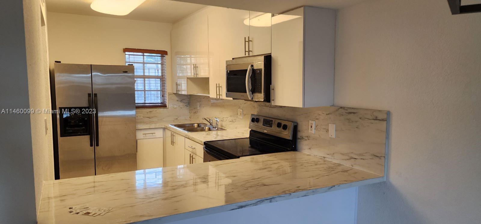 501 West 68th Street, Unit 4 Hialeah, FL 33014 - Photo 6 of 20 a kitchen with stainless steel appliances granite countertop a refrigerator a stove and a sink with wooden floors