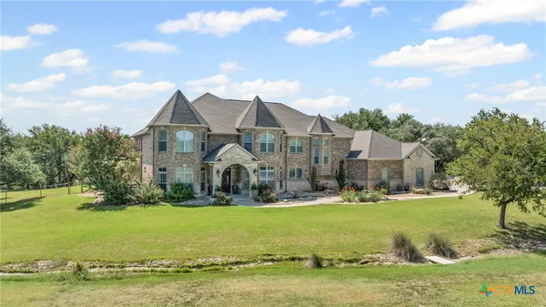 a view of a white house with a big yard plants and large trees