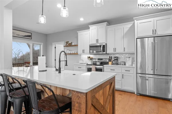 a kitchen with stainless steel appliances a table chairs refrigerator and microwave