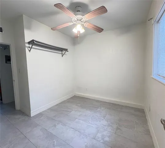 an empty room with a ceiling fan and a window