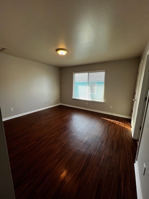 1172 Webberville Road Austin, TX 78721 - Photo 4 of 9 Unfurnished room featuring baseboards and dark wood finished floors