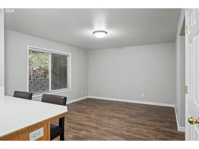a view of an empty room with window and wooden floor