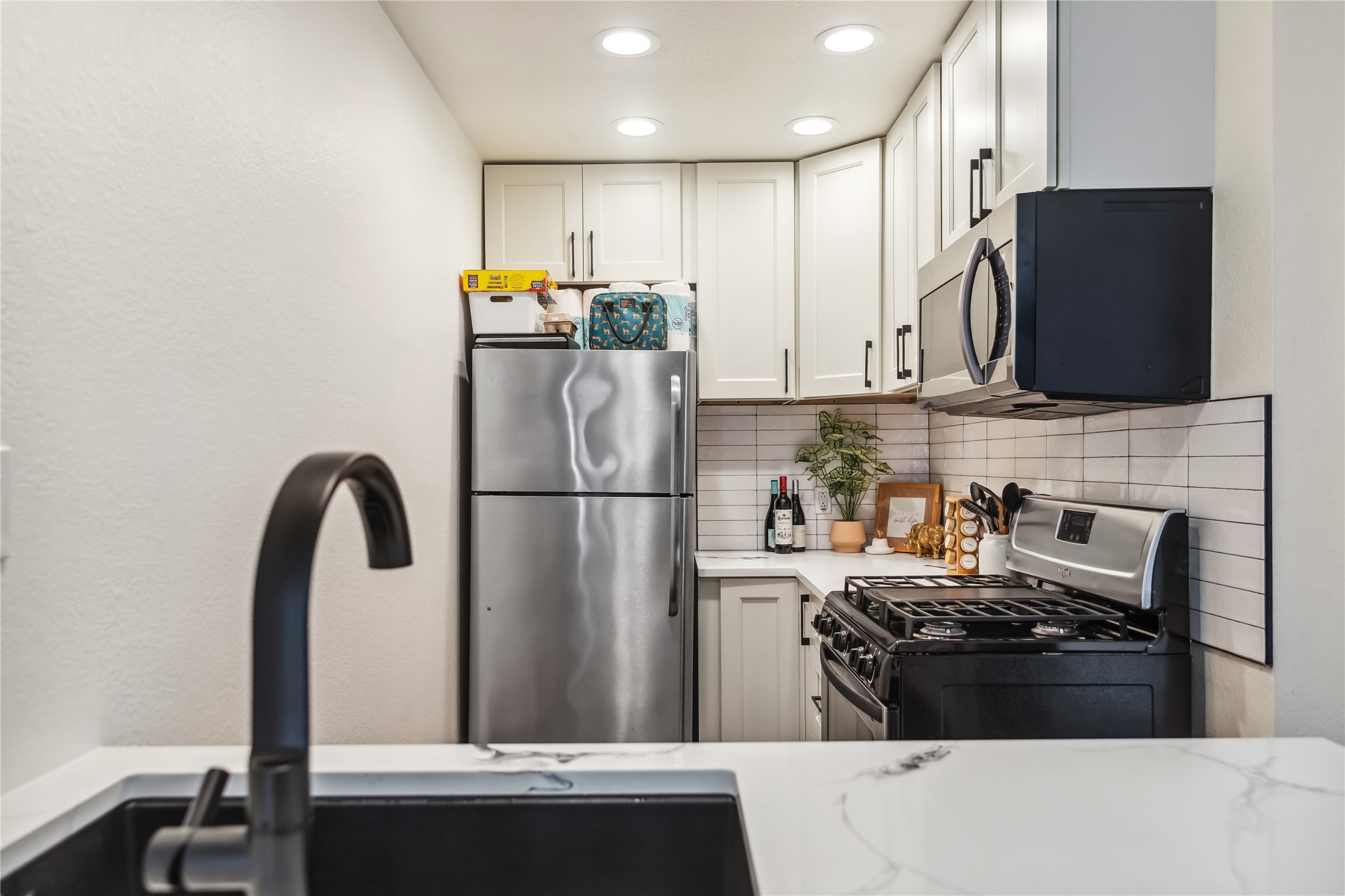 1313 East 52nd Street, Unit 101 Austin, TX 78723 - Photo 3 of 14 a kitchen with stainless steel appliances granite countertop a refrigerator stove and microwave