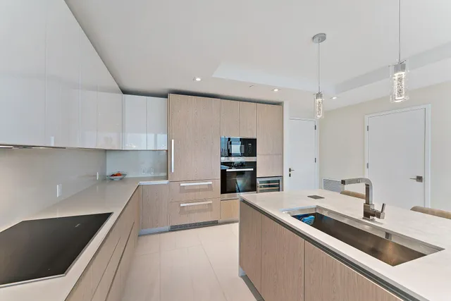 a view of a kitchen with a sink and dishwasher a stove top oven with wooden floor