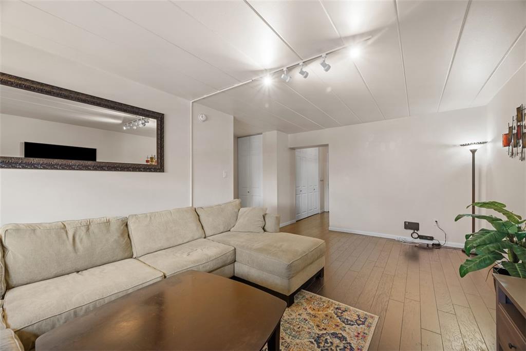 5 Bayard Road, Unit 121 Pittsburgh, PA 15213 - Photo 12 of 24 In the center of the room, a neutral sectional couch in soft beige tone anchors the space. Its plush cushions and clean lines create a comfortable yet stylish seating area. A few carefully chosen decor pieces, like a large area rug beneath the seating area, artwork on the walls, and a couple of minimalist side tables, complete the look, bringing balance and personality to the space without overcrowding it.