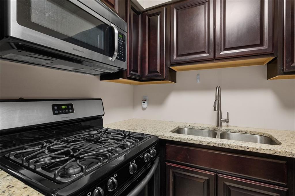 5 Bayard Road, Unit 121 Pittsburgh, PA 15213 - Photo 10 of 24 Stainless steel appliances add a sleek, modern touch. The combination of dark wood, clean lines, and warm lighting creates a balanced, comfortable environment that’s both aesthetically pleasing and functional, making it a perfect place to enjoy the process of cooking and preparing meals.