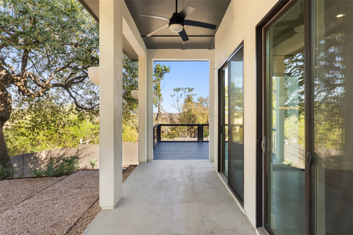 1303 Azie Morton Road, Unit 6 Austin, TX 78704 - Photo 13 of 40 This covered patio provides a crucial extension of the home's indoor living space, featuring a dark ceiling fan and large sliding glass doors for seamless transition. The space benefits from a private, elevated position that opens directly onto a deck overlooking scenic, treed views.