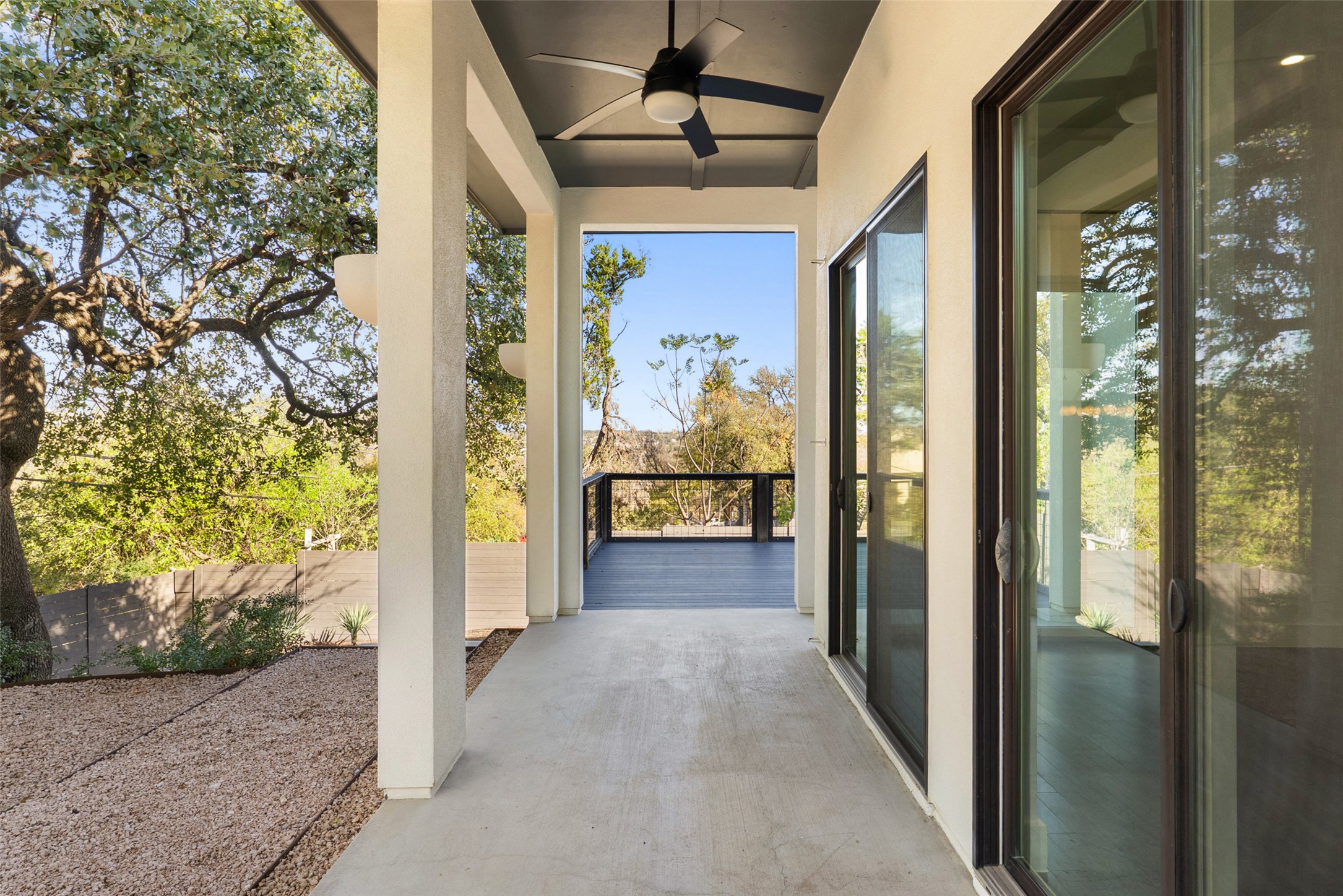 1303 Azie Morton Road, Unit 6 Austin, TX 78704 - Photo 13 of 40 This covered patio provides a crucial extension of the home's indoor living space, featuring a dark ceiling fan and large sliding glass doors for seamless transition. The space benefits from a private, elevated position that opens directly onto a deck overlooking scenic, treed views.