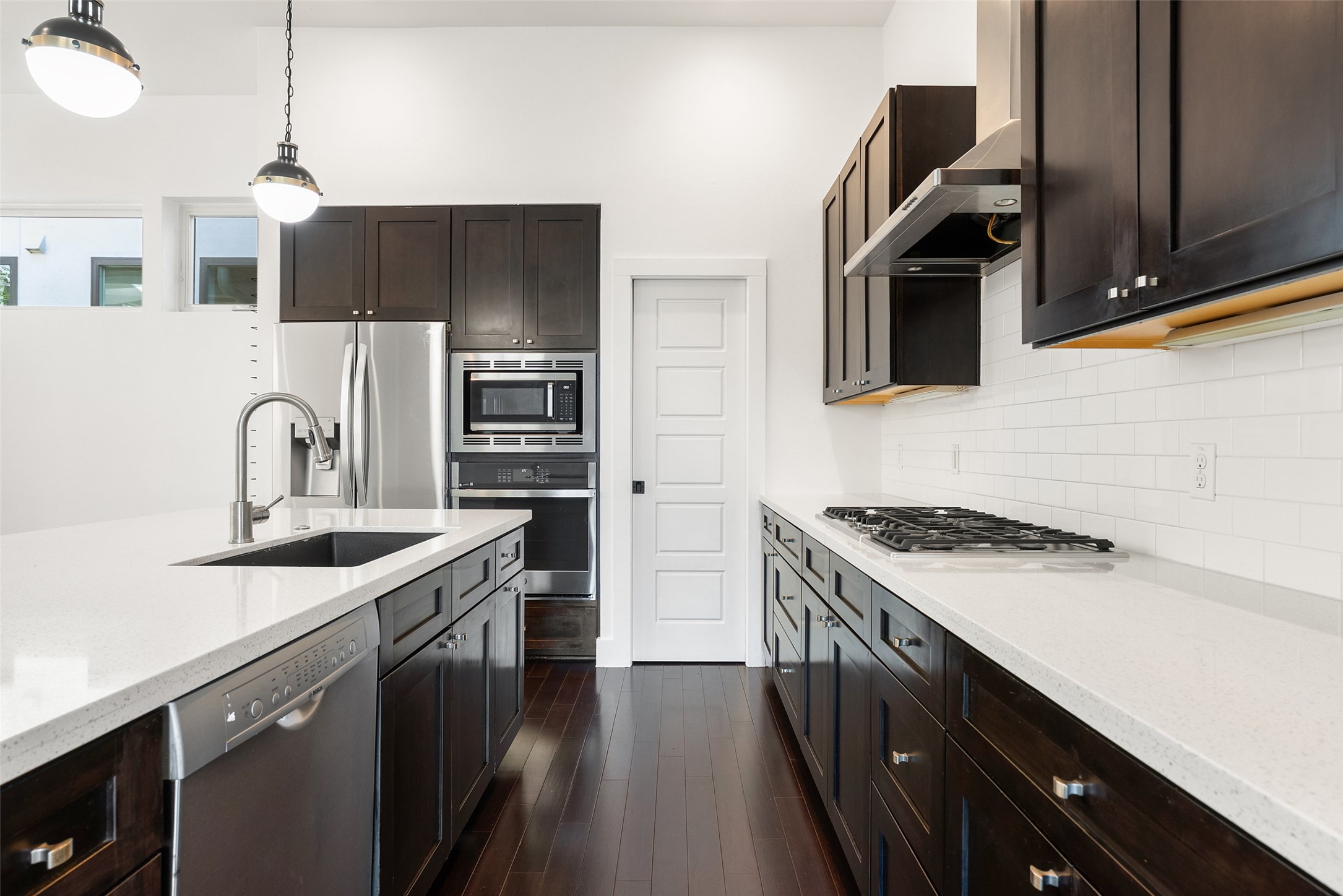 1303 Azie Morton Road, Unit 6 Austin, TX 78704 - Photo 19 of 40 This modern kitchen features dark mocha cabinetry paired with white quartz countertops and a subway tile backsplash. It offers a spacious island and includes a full suite of stainless steel appliances. The design is both highly functional and visually striking, with brand new oven.