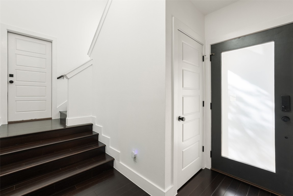 1303 Azie Morton Road, Unit 6 Austin, TX 78704 - Photo 31 of 40 This modern entryway features dark wood floors and stair treads dramatically contrasting with crisp white walls and trim. A large, dark-framed glass entry door maximizes light, and the dark staircase immediately establishes the home's contemporary, multi-level design.
