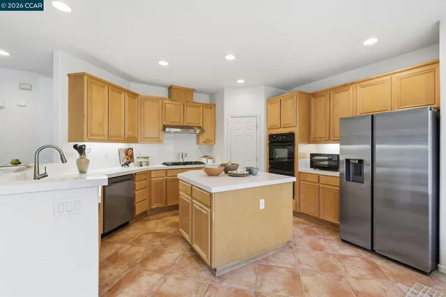 a kitchen with stainless steel appliances granite countertop a sink a stove a refrigerator and a refrigerator