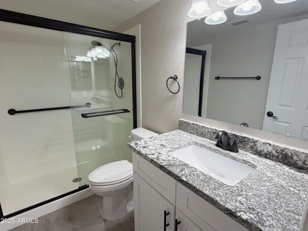 a bathroom with a granite countertop sink toilet and shower