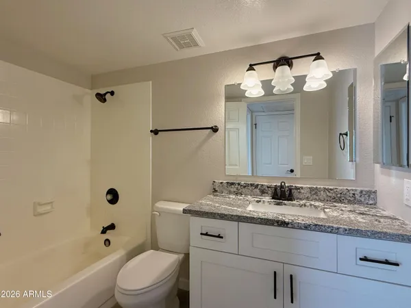 a bathroom with a granite countertop sink mirror vanity and toilet