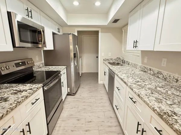 a kitchen with kitchen island granite countertop a sink stove and refrigerator