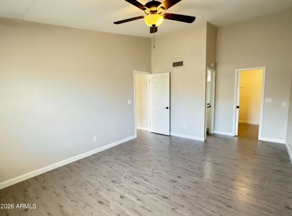 an empty room with wooden floor and a ceiling fan