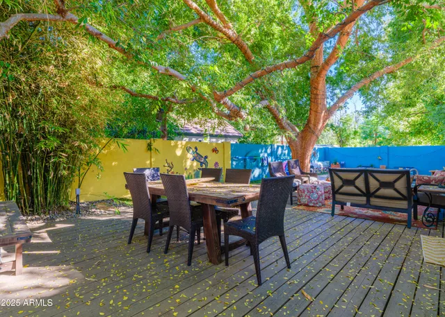 a view of a patio with table and chairs potted plants and large tree