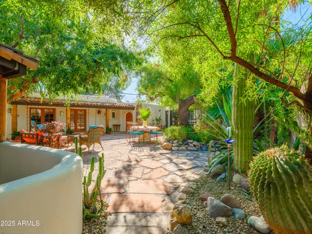 a view of a patio with table and chairs potted plants and large tree