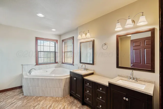 a bathroom with a bathtub double sink and mirror