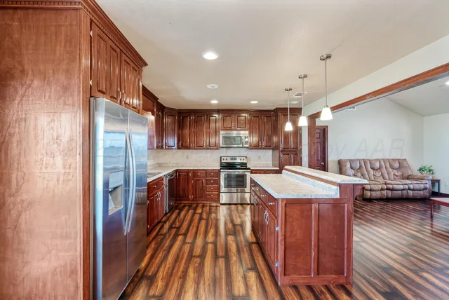 a dining hall with stainless steel appliances granite countertop a stove and a refrigerator