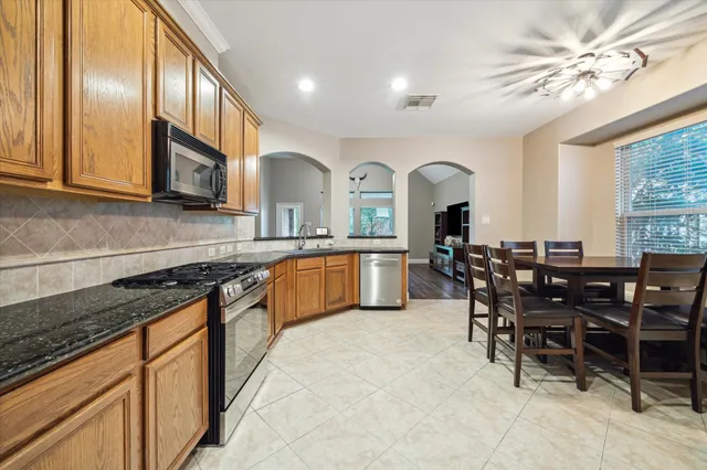 a kitchen with stainless steel appliances granite countertop a sink table and chairs