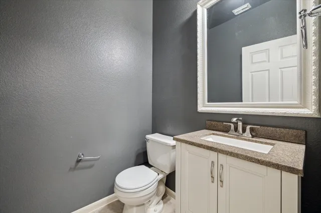 a bathroom with a granite countertop sink a toilet and a mirror