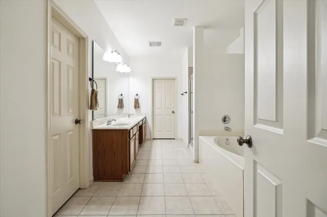 a spacious bathroom with a double vanity sink a mirror and a shower
