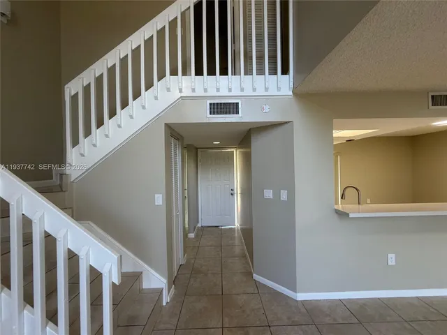 a view of staircase with white walls and fan