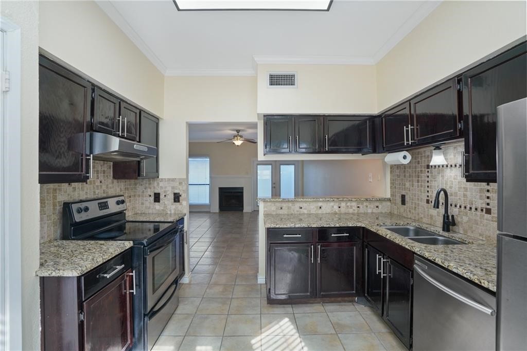 2713 St Joseph Street Corpus Christi, TX 78418 - Photo 5 of 17 a kitchen with stainless steel appliances granite countertop a stove top oven a sink dishwasher and a refrigerator with wooden cabinets