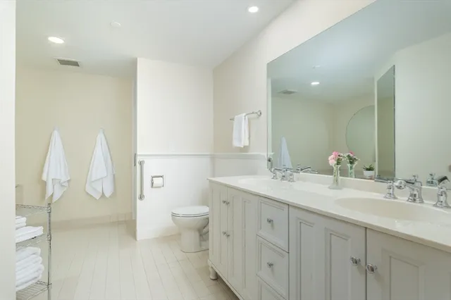 a bathroom with a double vanity sink toilet and a mirror