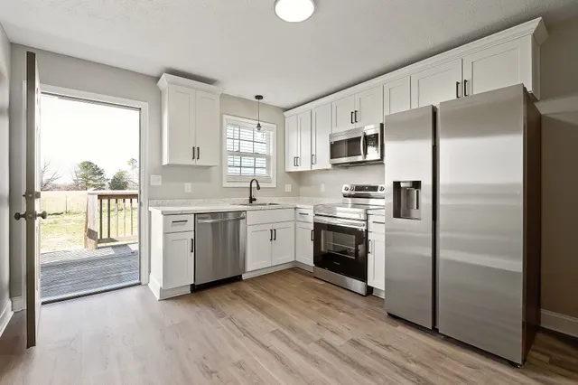 a kitchen with a refrigerator stove and wooden floor