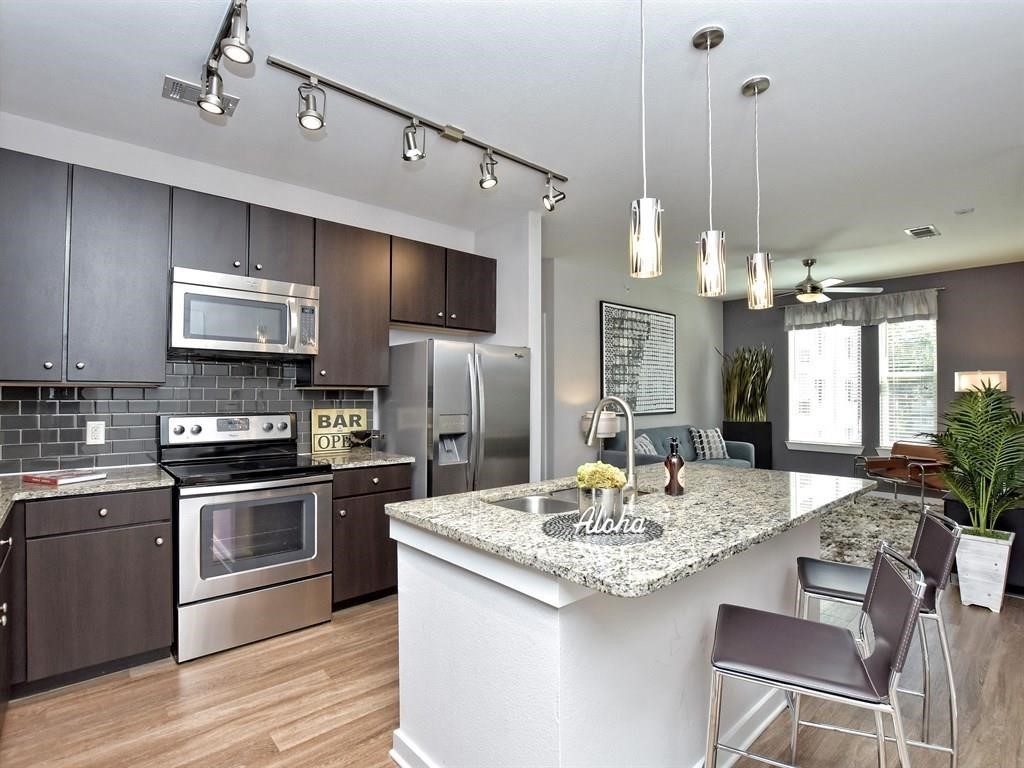 a kitchen with kitchen island granite countertop a sink stainless steel appliances and cabinets