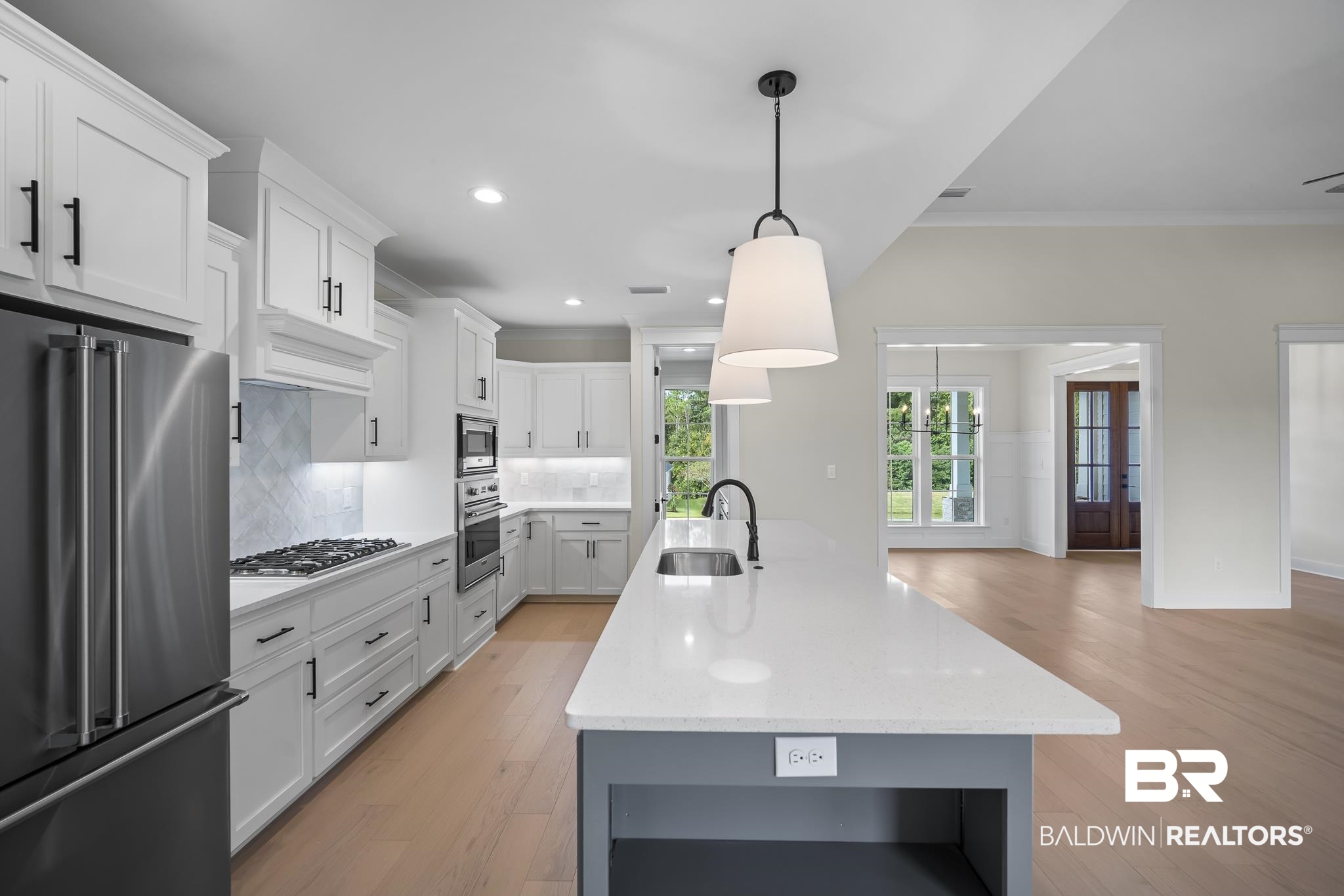 21826 Veranda Boulevard Fairhope, AL 36532 - Photo 10 of 42 Kitchen featuring appliances with stainless steel finishes, white cabinetry, pendant lighting, light wood finished floors, and backsplash
