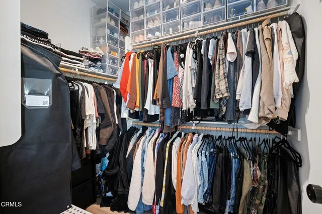a view of walk in closet with clothes and shoes