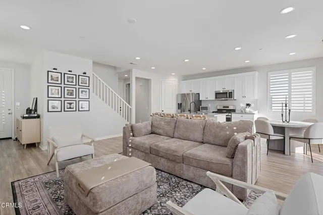 a living room with furniture kitchen view and a wooden floor