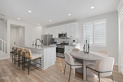 a kitchen with stainless steel appliances granite countertop a dining table chairs and granite counter tops