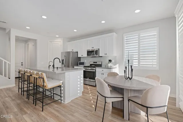 a kitchen with stainless steel appliances granite countertop a dining table chairs and granite counter tops