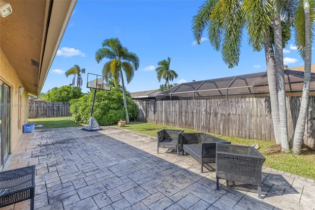a view of a backyard with chairs potted plants and wooden fence