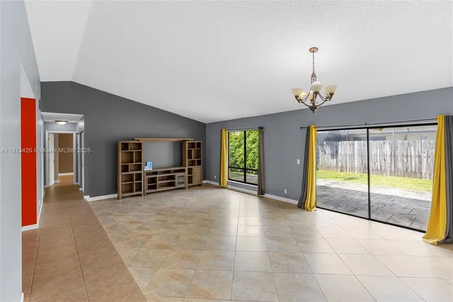 a view of an empty room with window and chandelier