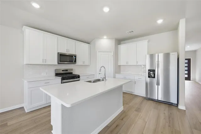 a kitchen with white cabinets and stainless steel appliances