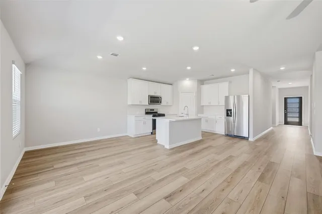 a view of kitchen with kitchen island wooden floor center island and stainless steel appliances