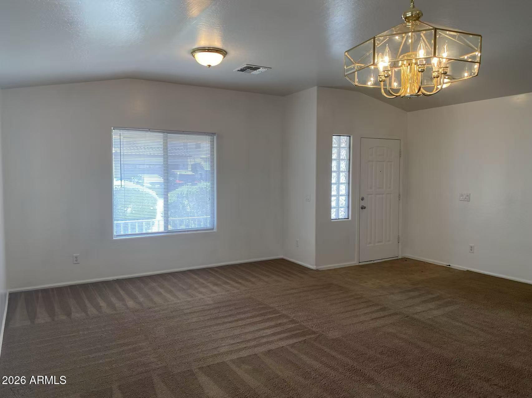 9124 West Heber Road Tolleson, AZ 85353 - Photo 3 of 26 an empty room that has a chandelier fan and a window
