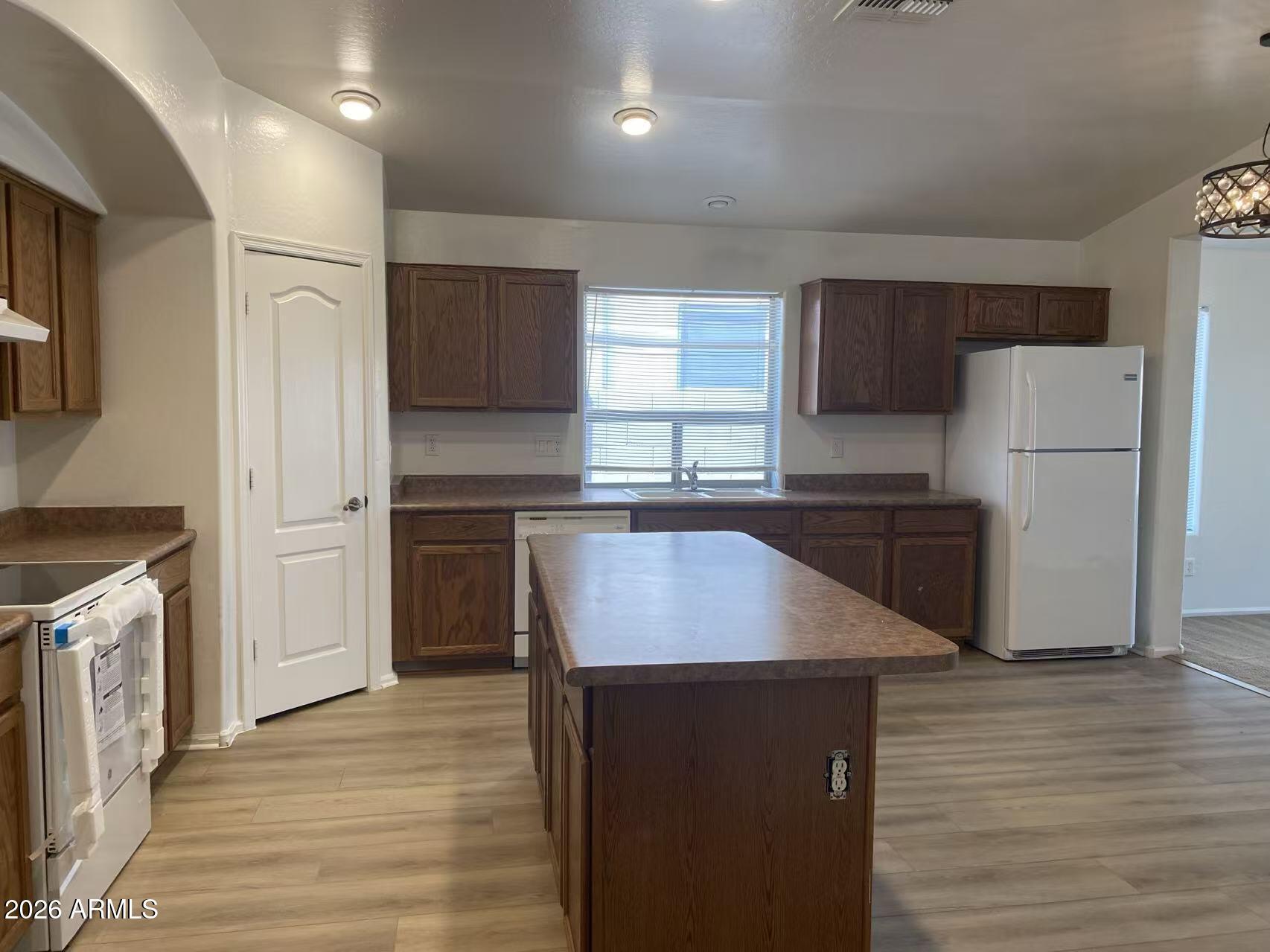 9124 West Heber Road Tolleson, AZ 85353 - Photo 7 of 26 a kitchen with refrigerator cabinets and wooden floor