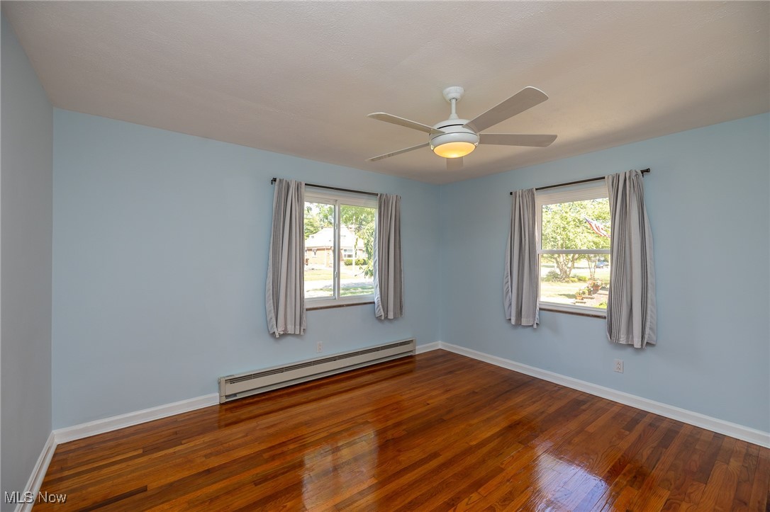 21475 Eaton Road Cleveland, OH 44126 - Photo 27 of 31 Unfurnished room featuring dark wood-type flooring, baseboard heating, ceiling fan, and a wealth of natural light