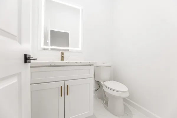 a bathroom with a toilet sink vanity and mirror