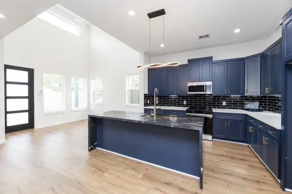a kitchen with stainless steel appliances granite countertop a sink a stove and wooden floors